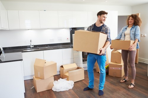 Professional movers carrying furniture through a residential street in Highams Park