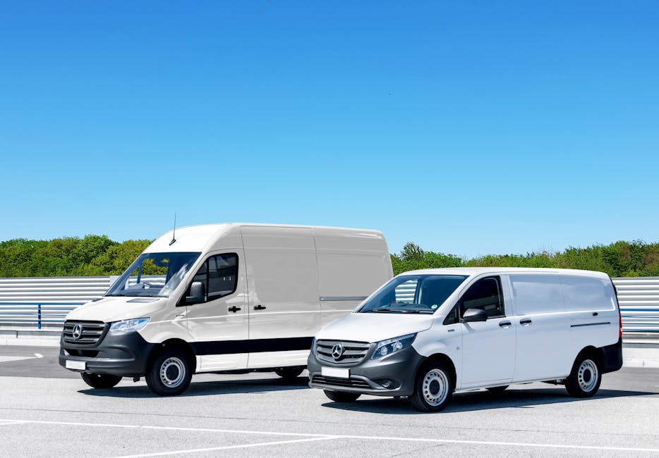 Two white Mercedes-Benz panel vans parked on a paved road during daytime, with the larger van positioned behind the smaller one. The larger van has a high roof, a sliding side door, and visible side m